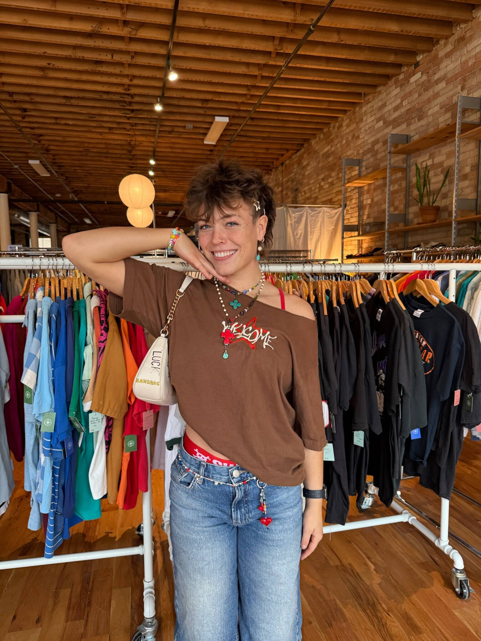 Emily stands in a store with short dark brown hair, posing with her hand on the side of her face
